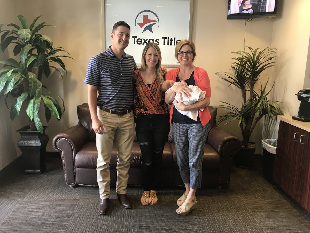 Realtor, Tamra Holden, standing with a family while holding their baby after the happy family bought a new house.